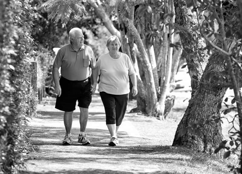 eldre par går tur i parken