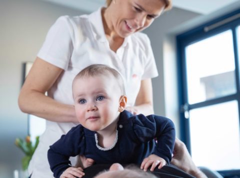 Terapeut som behandler en baby ved manipulasjon på ryggen