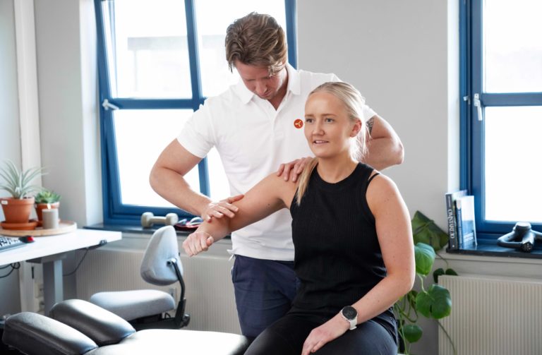 Fysioterapeut undersøker skulder på pasient